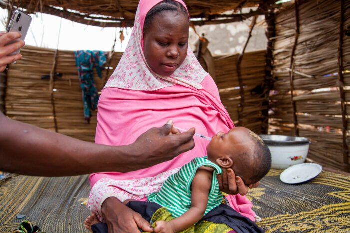 Woman holding infant receiving medication 