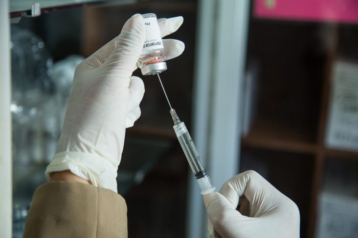 Image of medically gloved hands retrieving medicine from a vial